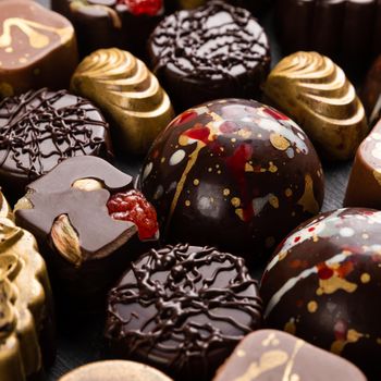 Luxury chocolate pieces on the black background, top view
