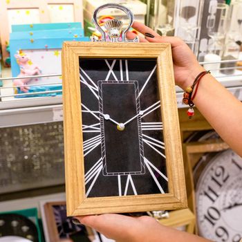 Woman holding big wall clock at the store