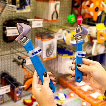 Woman holding a blue adjustable wrench at the store