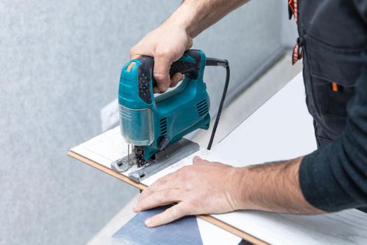 Man working with jigsaw on white wood laminate