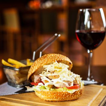 Caesar burger with french fries and glass of red wine