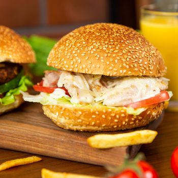 Caesar burger, french fries on the wood plate close up