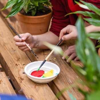 Kids dipping paint plate with a brush top view