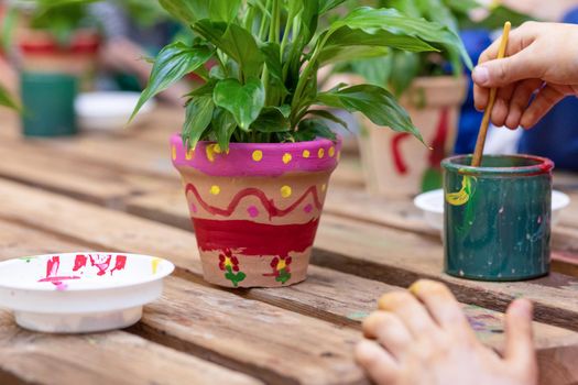 Children are painting potted plants made of pottery close up