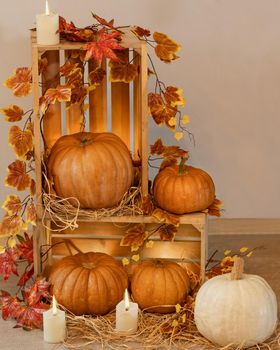 Halloween Pumpkins in the wooden crates with candles, straw, autumn leaves