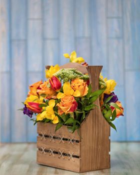 Colorful flower bouquet in the wood box with blue background