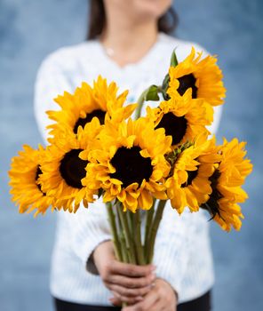 Woman holding sunflowers with blue background
