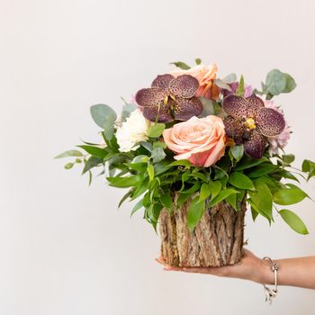 Woman holding beautiful flower bouquet in the wooden pot