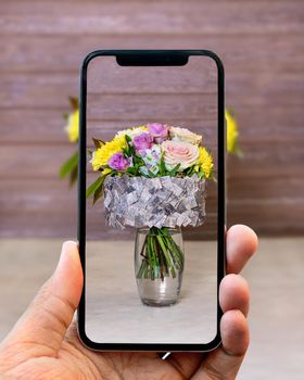 Taking photo of flower bouquet in the vase with mobile phone