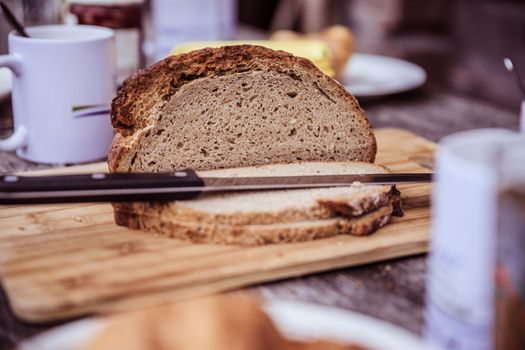 Fresh dark crisp bread for breakfast on an alpine hut. Wooden cutting board and milk in glass bottle.