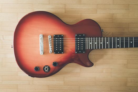 Electronic guitar in sunburst optic lying on the wooden floor