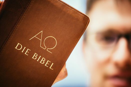 Young preacher is holding the holy bible, praying