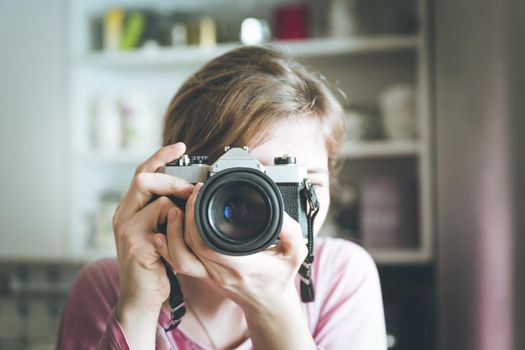 Young girl is taking a picture with a vintage camera