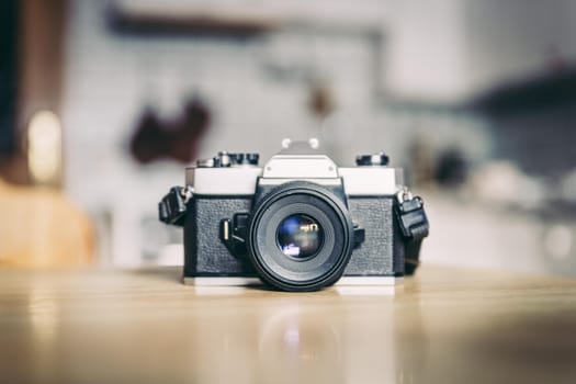 Retro vintage photography camera on kitchen table, blurry background