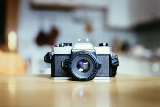 Retro vintage photography camera on kitchen table, blurry background