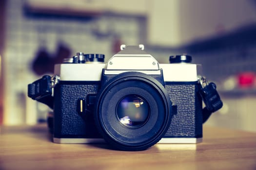 Retro vintage photography camera on kitchen table, blurry background