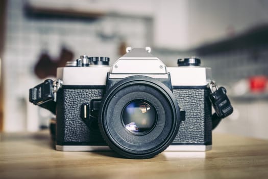 Retro vintage photography camera on kitchen table, blurry background