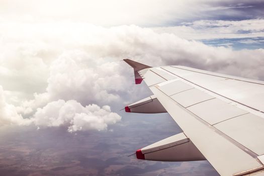 View of a grey airplane wing through the aircraft window. Sunshine, global warming.