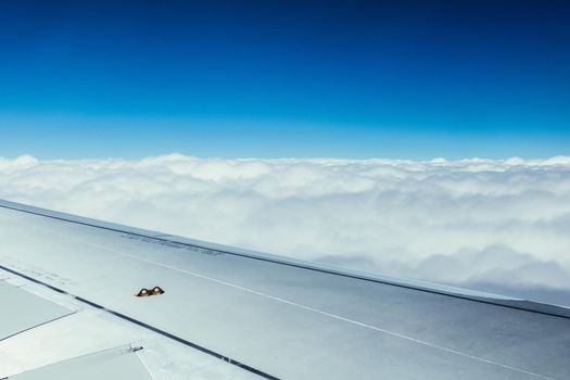 View of a grey airplane wing through the aircraft window. Global warming.