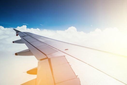 View of a grey airplane wing through the aircraft window. Sunshine, global warming.