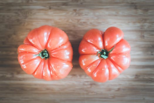 Close up picture of oxheart tomatoes on a bamboo wood plate.