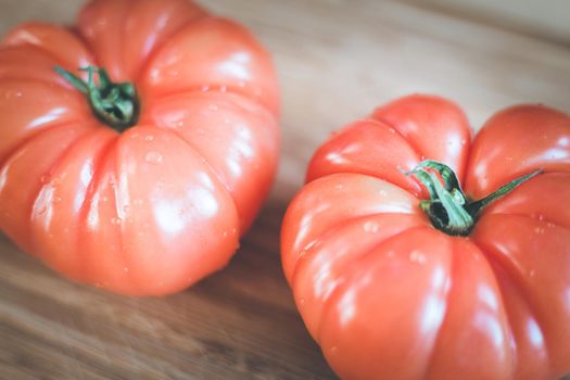 Close up picture of oxheart tomatoes on a bamboo wood plate.