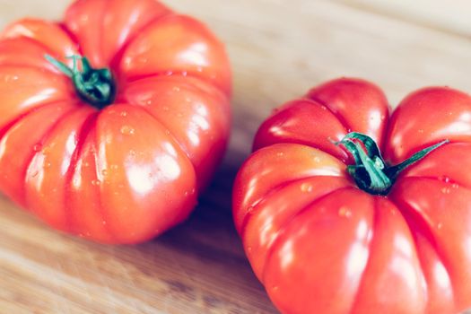 Close up picture of oxheart tomatoes on a bamboo wood plate.