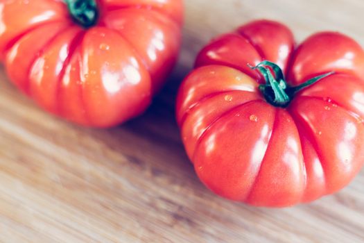 Close up picture of oxheart tomatoes on a bamboo wood plate.