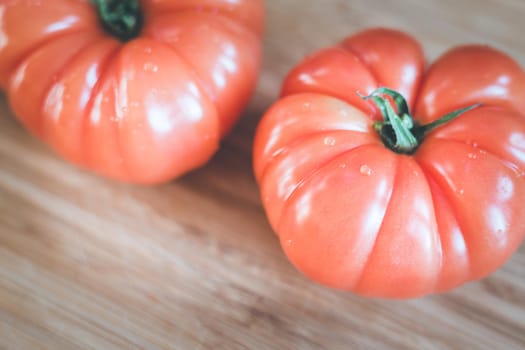 Close up picture of oxheart tomatoes on a bamboo wood plate.