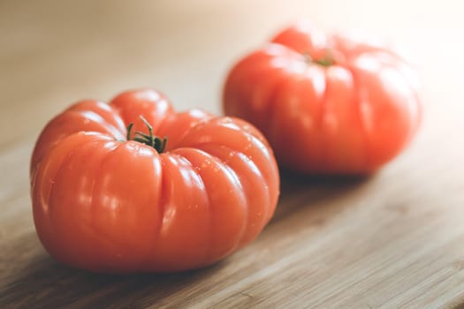 Close up picture of oxheart tomatoes on a bamboo wood plate.