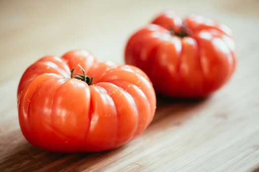 Close up picture of oxheart tomatoes on a bamboo wood plate.