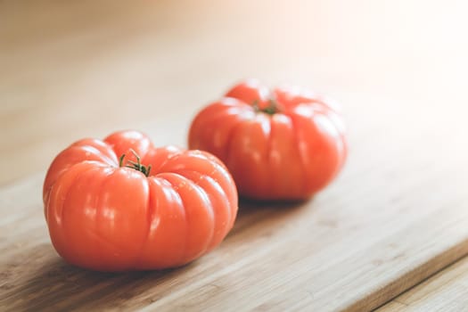Close up picture of oxheart tomatoes on a bamboo wood plate.