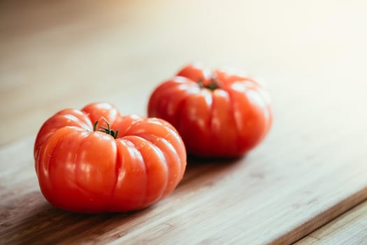 Close up picture of oxheart tomatoes on a bamboo wood plate.