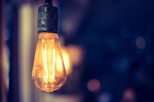 Close up picture of a hanging orange lightbulb in a restaurant or café