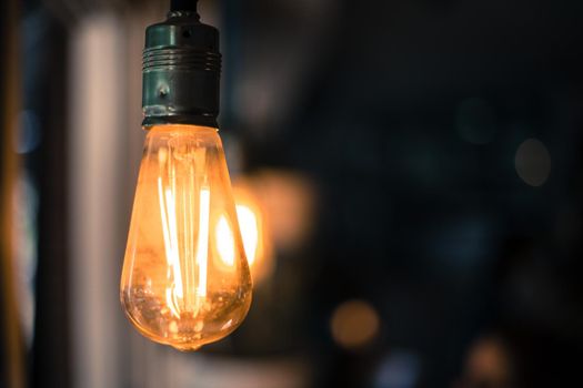 Close up picture of a hanging orange lightbulb in a restaurant or café