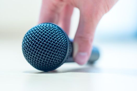 Close up picture of a hand which is holding a black microphone.