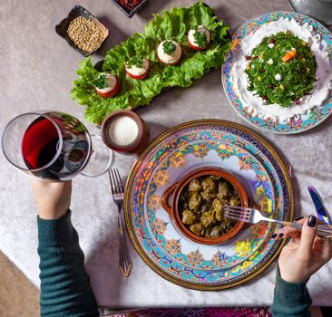 Woman eating Dolma, with red wine top view