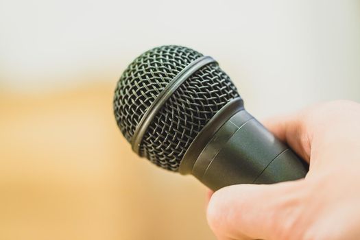 Close up picture of a hand which is holding a black microphone.
