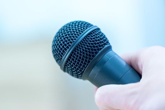 Close up picture of a hand which is holding a black microphone.