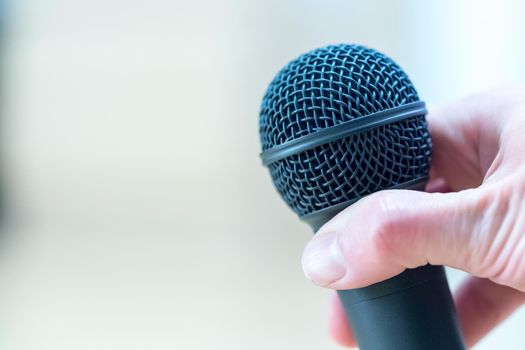 Close up picture of a hand which is holding a black microphone.