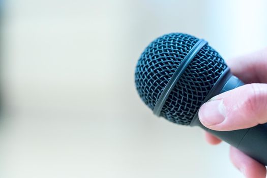 Close up picture of a hand which is holding a black microphone.