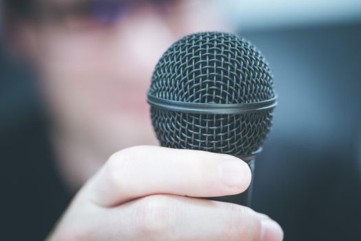 Microphone in the foreground, man taking into it in the blurry background