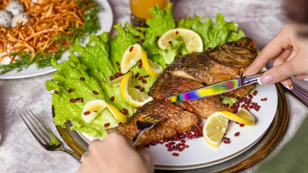 Woman eating a grilled whole fish with a lemon