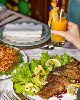 Woman eating a grilled whole fish with a lemon and juice