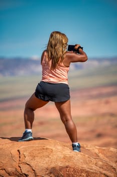 Back view of a african american female tourist photographing a National Park landscape.