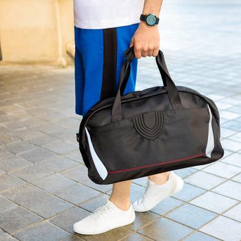 Young man holding a black sport bag close up