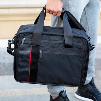 Young man holding a black sport bag close up