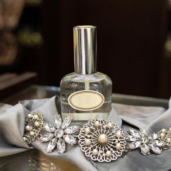 Perfume flacon with jewellery on the white background