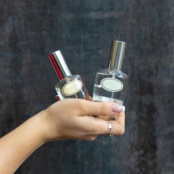 Woman holding perfume flacons with silver background