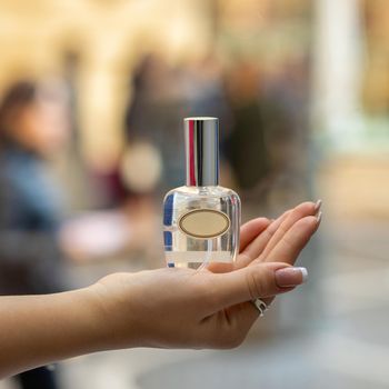 Woman holding perfume flacon with blur background